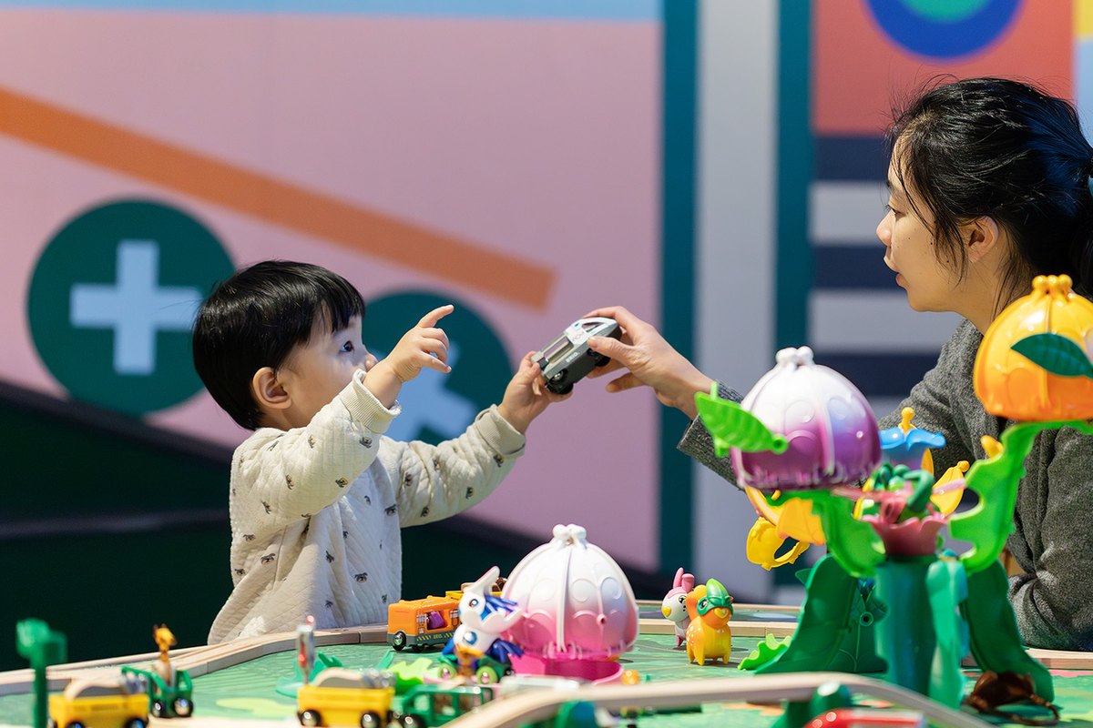 A small boy and his mother playing with toy cars on a colourful play table in Teknoleket at Tekniska museet