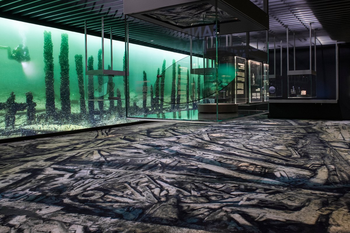 The full-scale Resande Man exhibition at Vrak, with the wreck printed on the floor and green-lit underwater photographs around it