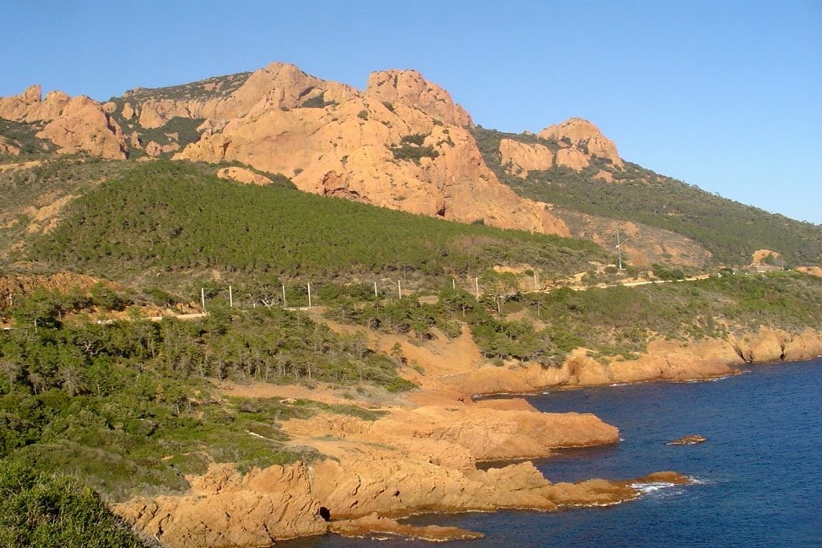 The red peaks of the Estérel above green maquis and the rocky shore near Agay