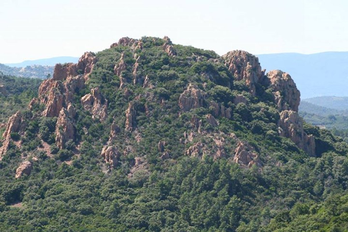 A craggy red-rock summit of the Estérel massif rising above green pine and cork-oak forest