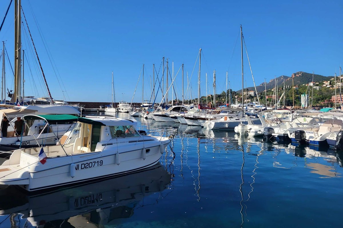 Motor boats and sailing masts moored in the Port de la Figueirette under a blue sky