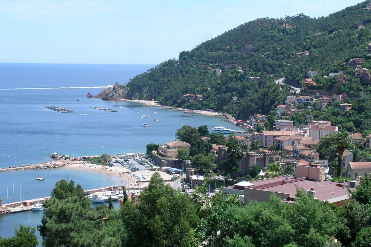 Théoule seen from the wooded heights: the village roofs, the port and its beaches curving along the bay