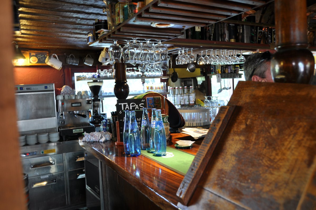 The wooden bar with hanging glasses at Le Café Brun in Biot village