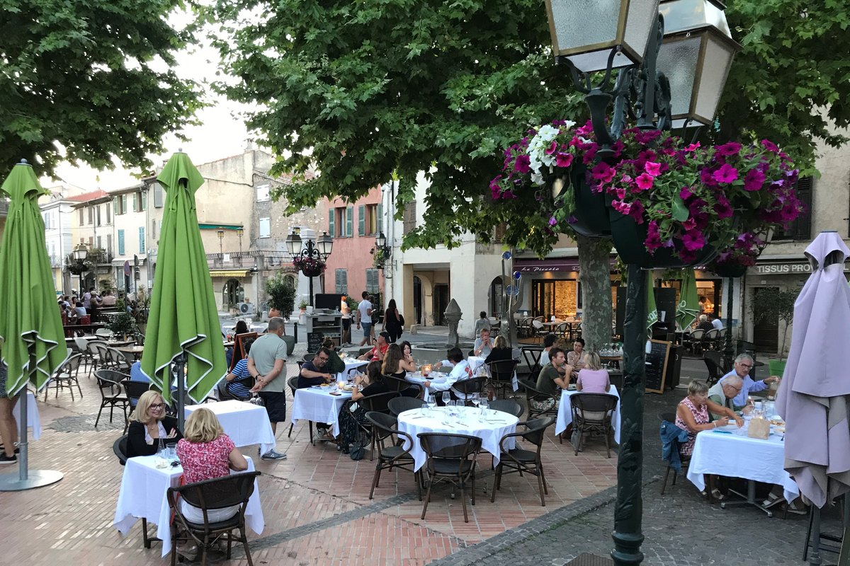 Diners on the terrace of Le Café de la Poste under the trees of Biot's village square