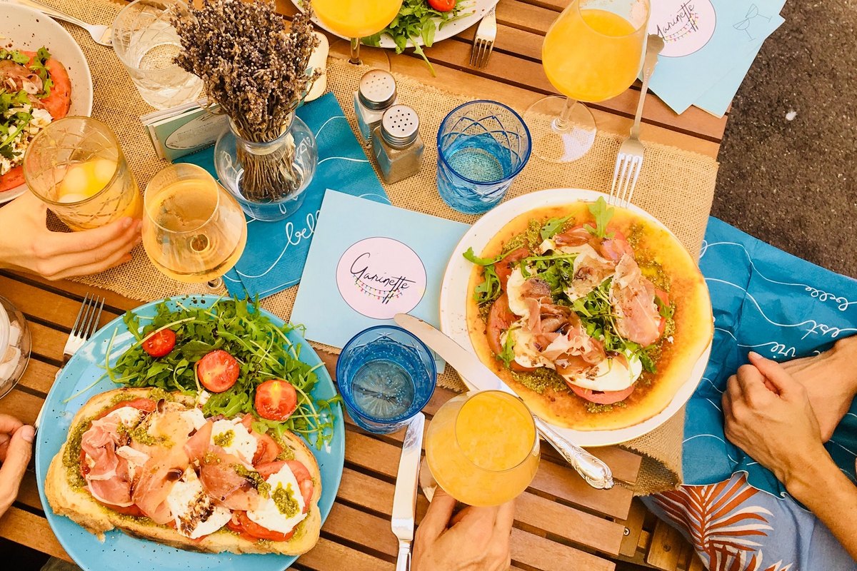 Plates, glasses and juices shared round a wooden terrace table at Garinette in Valbonne village