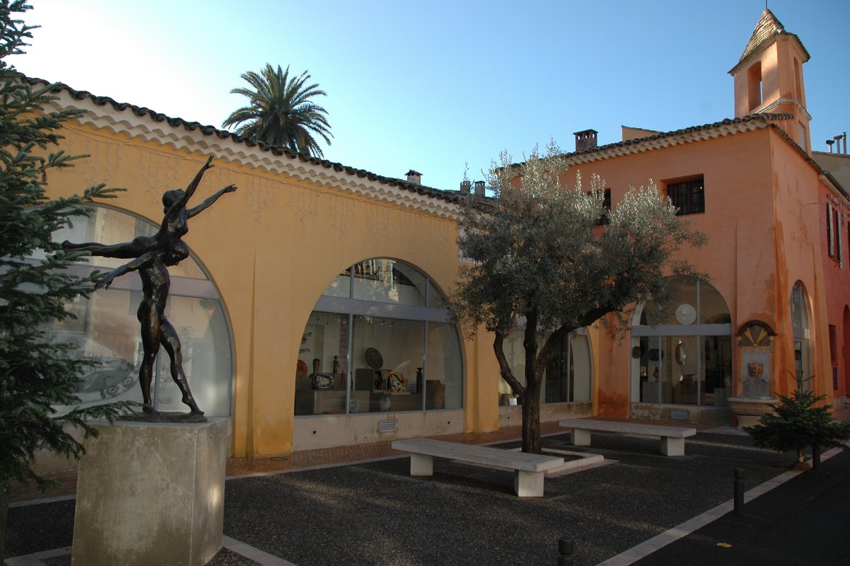 The arcaded former hospital housing the Musée d'Histoire et de Céramique Biotoises, with a bronze sculpture in front