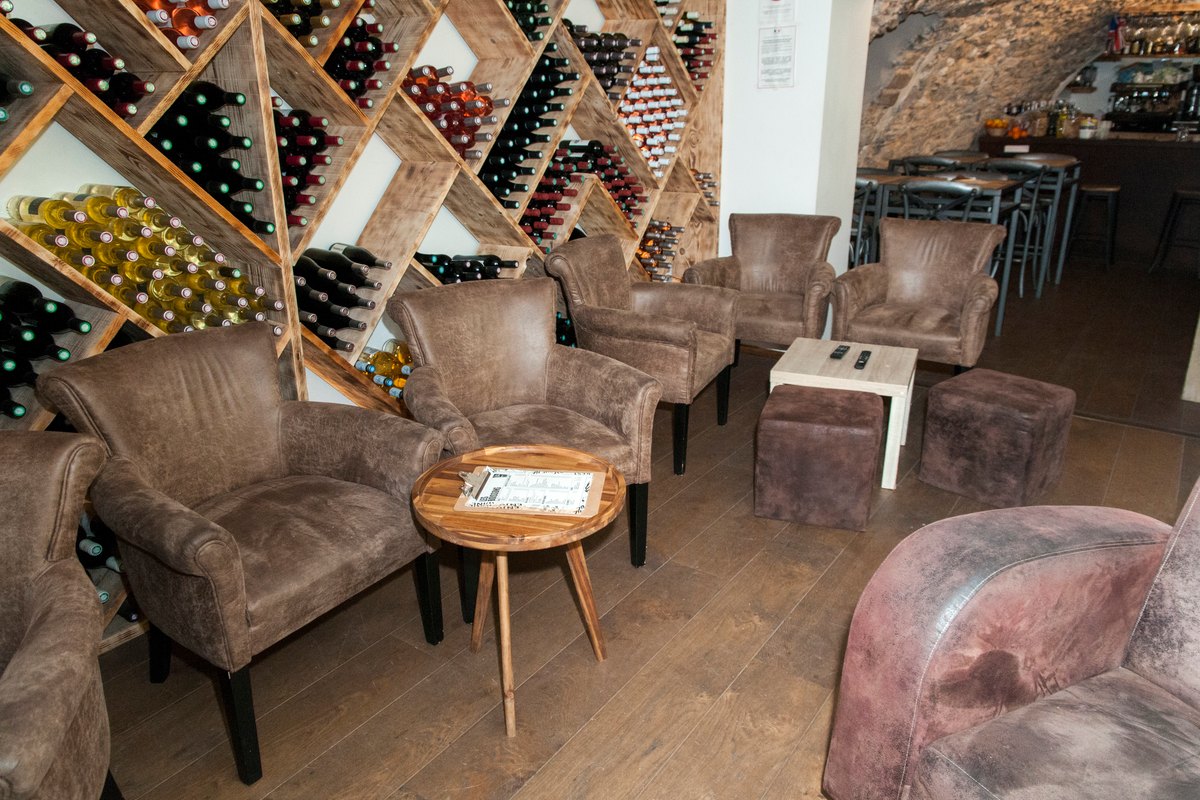 Leather armchairs beneath wine racks in the lounge of Trio Vino in Biot