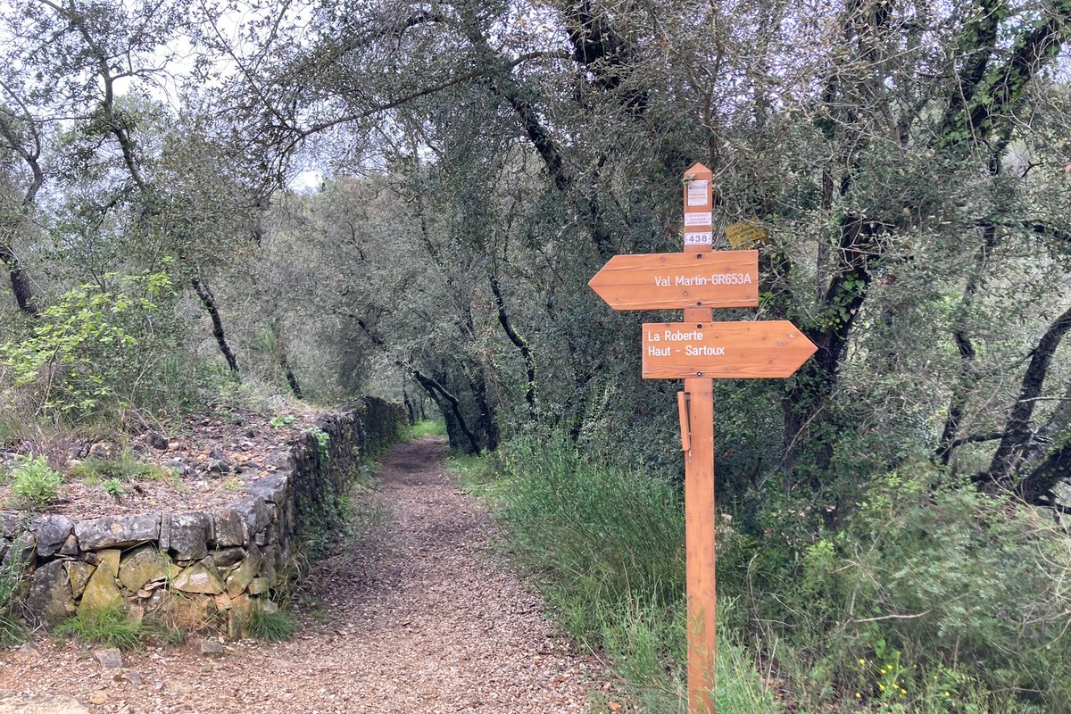 A waymark post beside a drystone wall and olive trees on the Val Martin walk in Valbonne