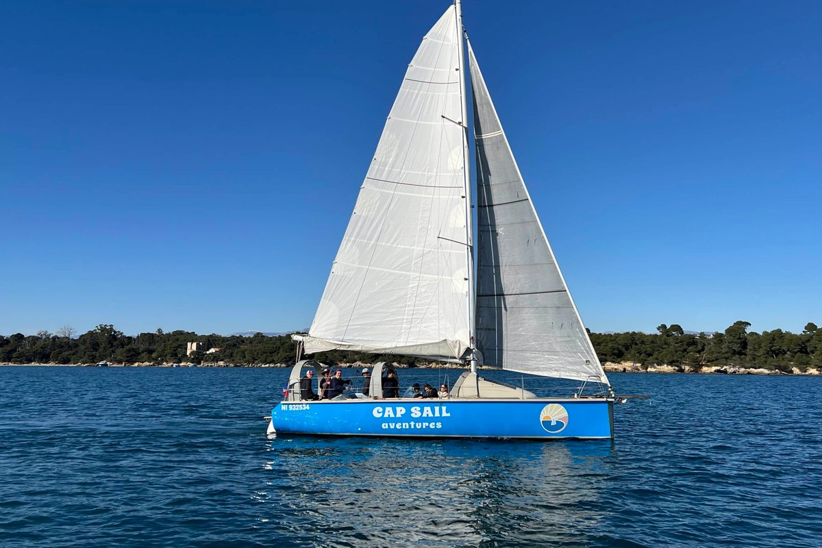 The Cap Sail Aventures sailing boat under full sail on a blue sea off the coast