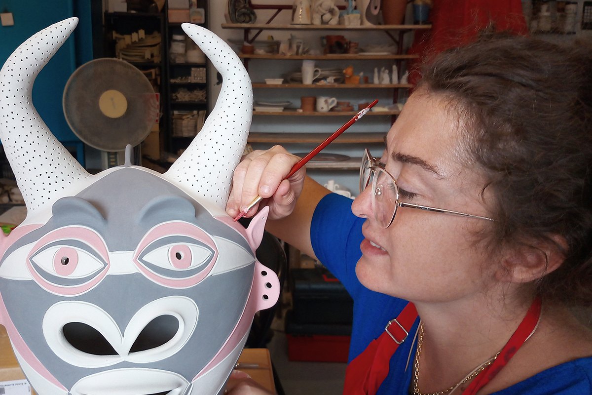 Ceramicist Karine Gervasi painting a white bull's-head mask in her Vallauris workshop