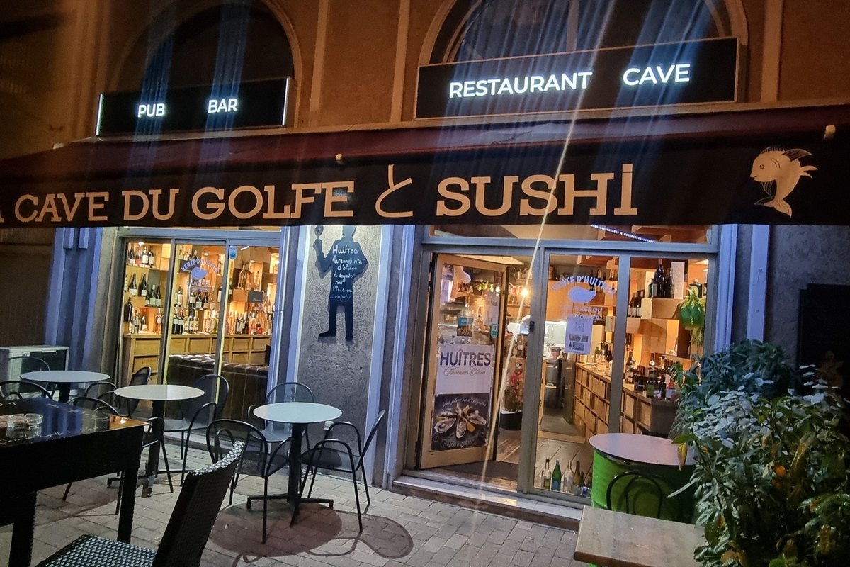 The lit shopfront and pavement tables of La Cave du Golfe & Sushi on avenue Pablo Picasso in Vallauris