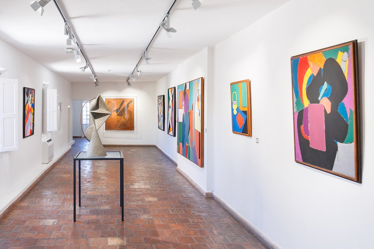 A white gallery with terracotta floor tiles and colourful abstract paintings at the Musée Magnelli, musée de la céramique in Vallauris