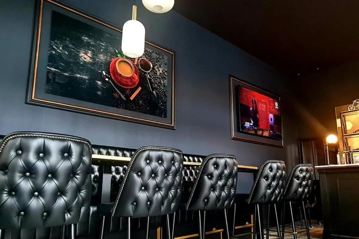 Black quilted bar stools and dark walls inside the retro-chic Réservoir Caffè in Golfe-Juan