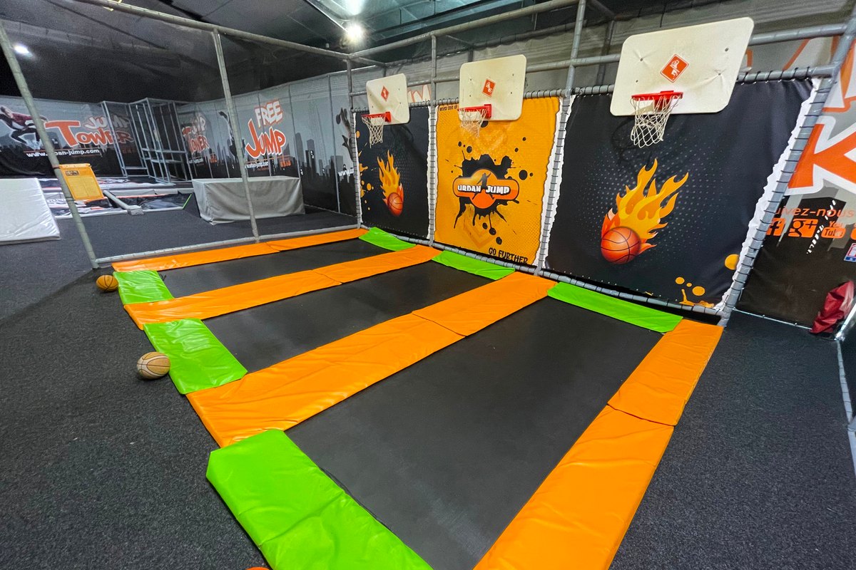 Trampoline lanes with basketball hoops and orange and green padding at the Urban Jump trampoline park in Vallauris