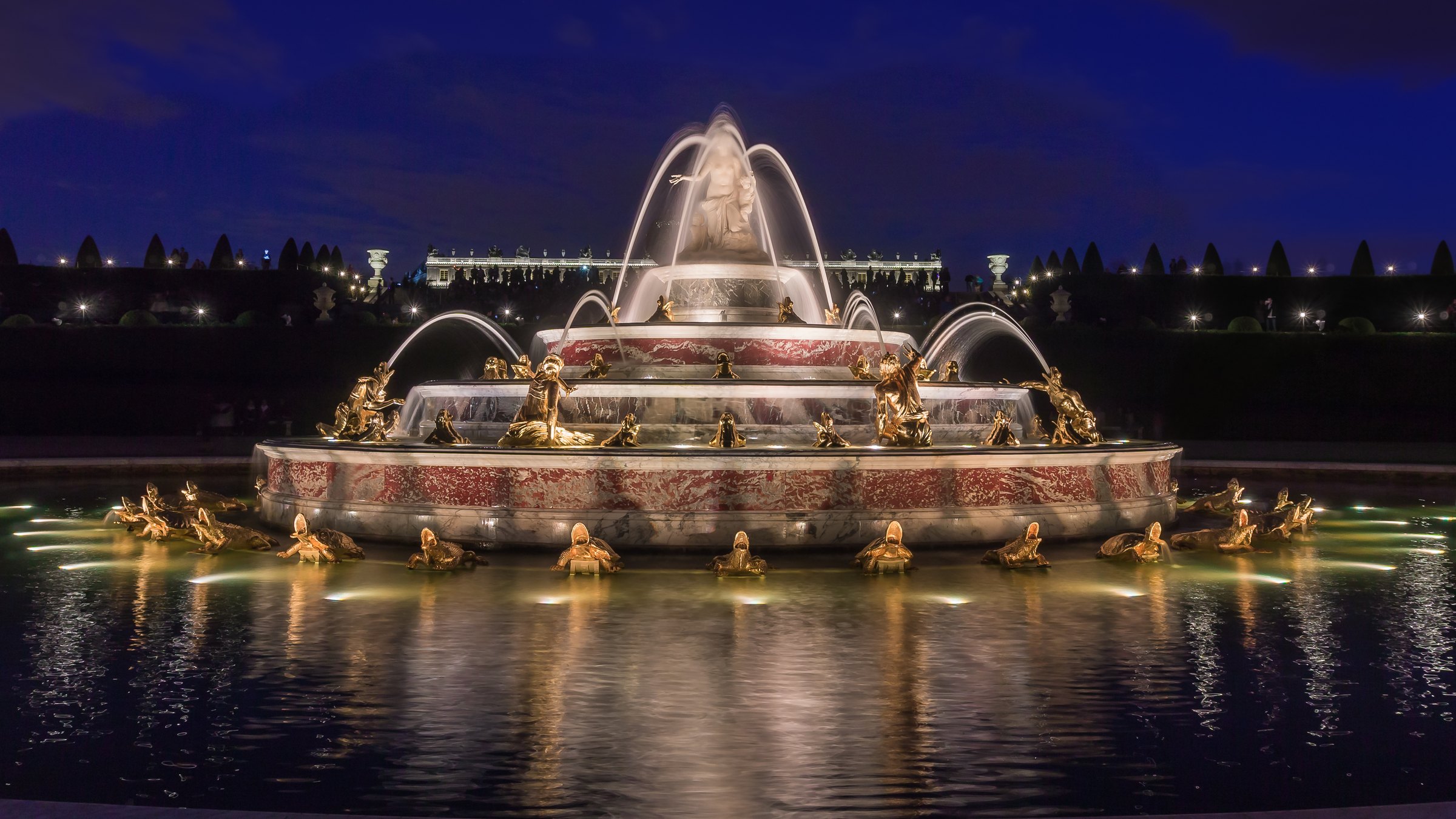 A fountain lit up at night in the gardens of Versailles