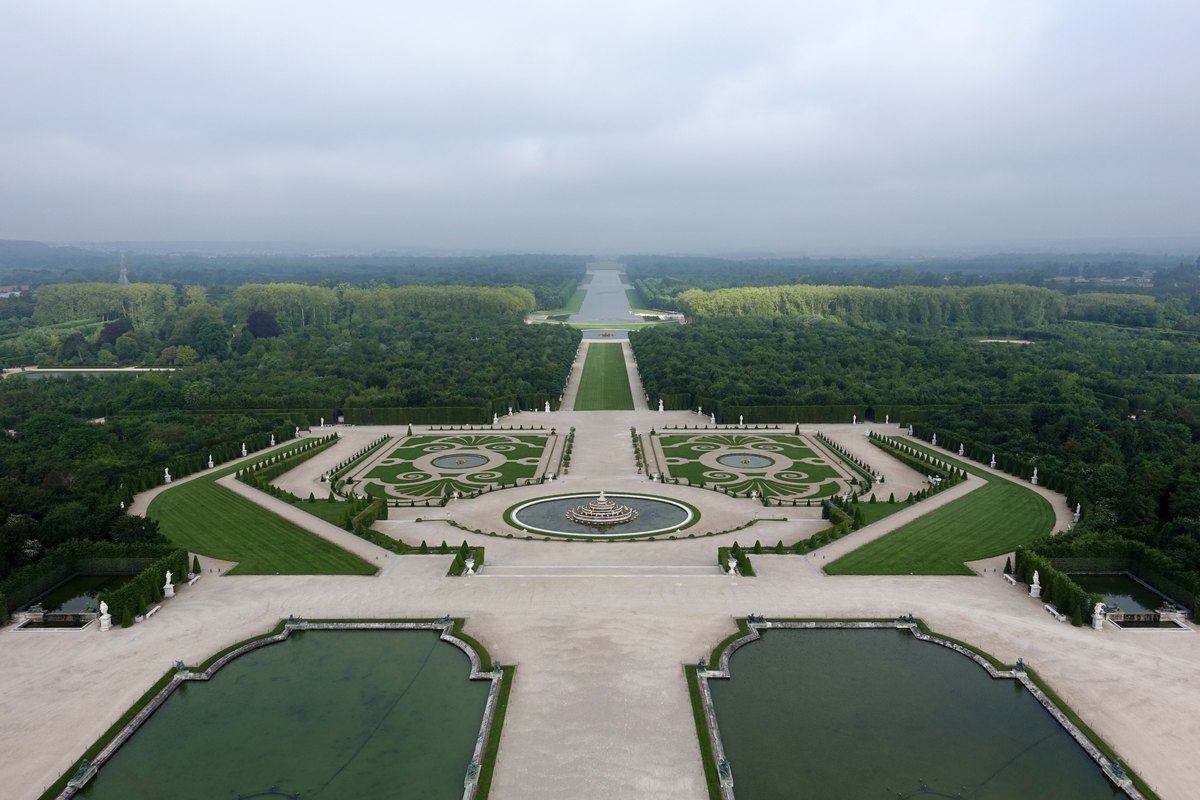 The parterres and fountains of the Gardens of Versailles seen from above, with the Grand Canal stretching to the horizon