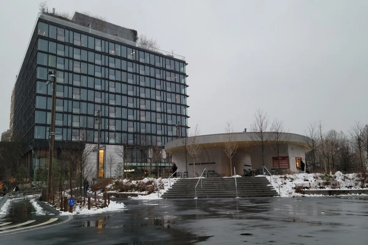 Exterior view of 1 Hotel Brooklyn Bridge glass façade and entrance pavilion in Brooklyn Bridge Park, winter scene