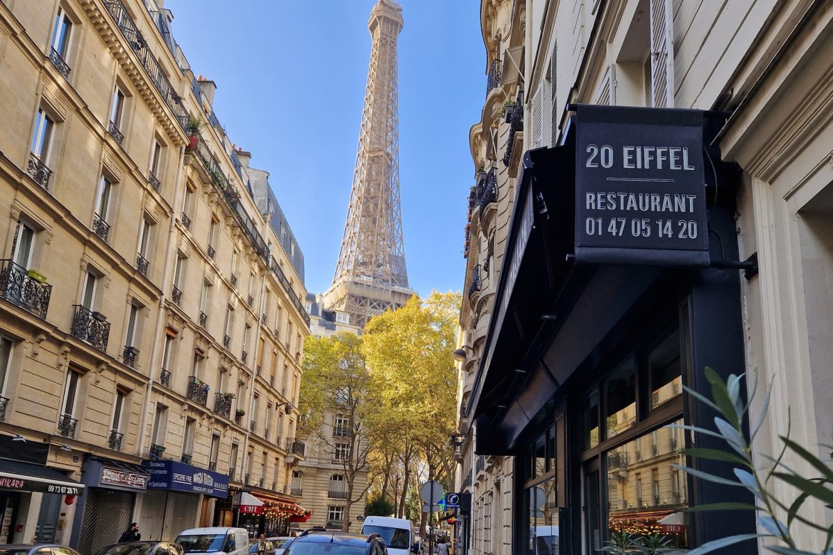20 Eiffel restaurant storefront sign on a Paris street with the Eiffel Tower framed between buildings