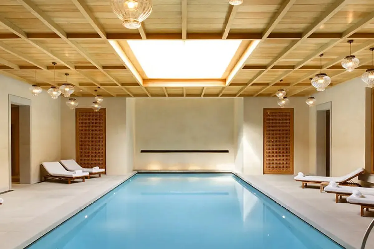 Elegant indoor spa pool with wooden coffered ceiling, skylight and lounge chairs