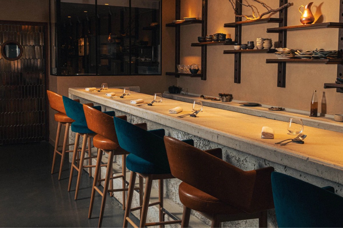 Dining bar with velvet stools, open shelving of ceramics, and warm lighting at Accents Table Bourse