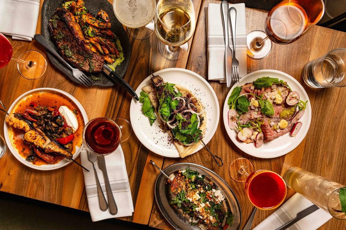 Overhead shot of a shared table with multiple Mediterranean-style dishes, wine and cocktails at Adraba