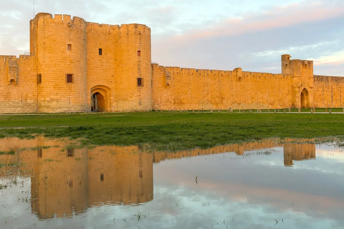 The ramparts of Aigues-Mortes reflected in water at sunset