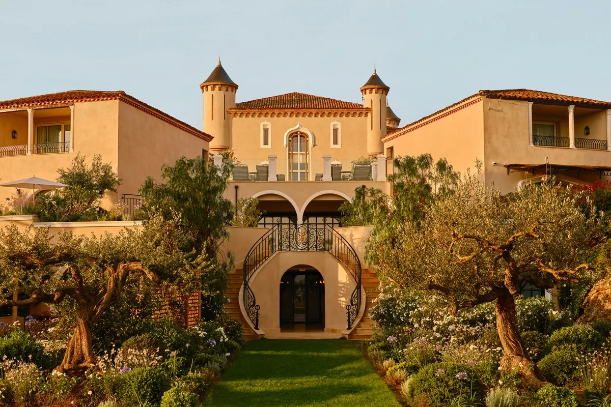 Château façade at golden hour with twin turrets, garden path and curved staircase entrance