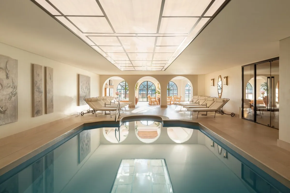 Indoor spa pool with arched windows, loungers and skylight ceiling