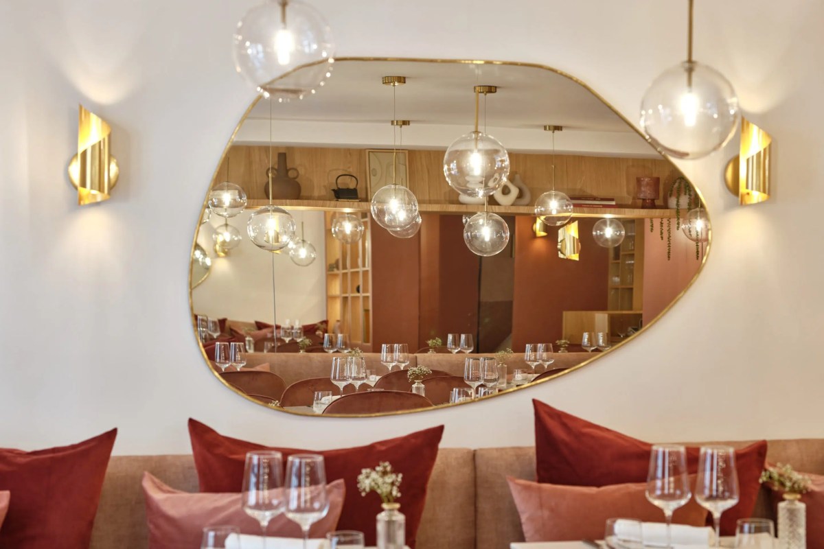 Dining room reflected in an oval mirror, with pendant lights and red banquette seating