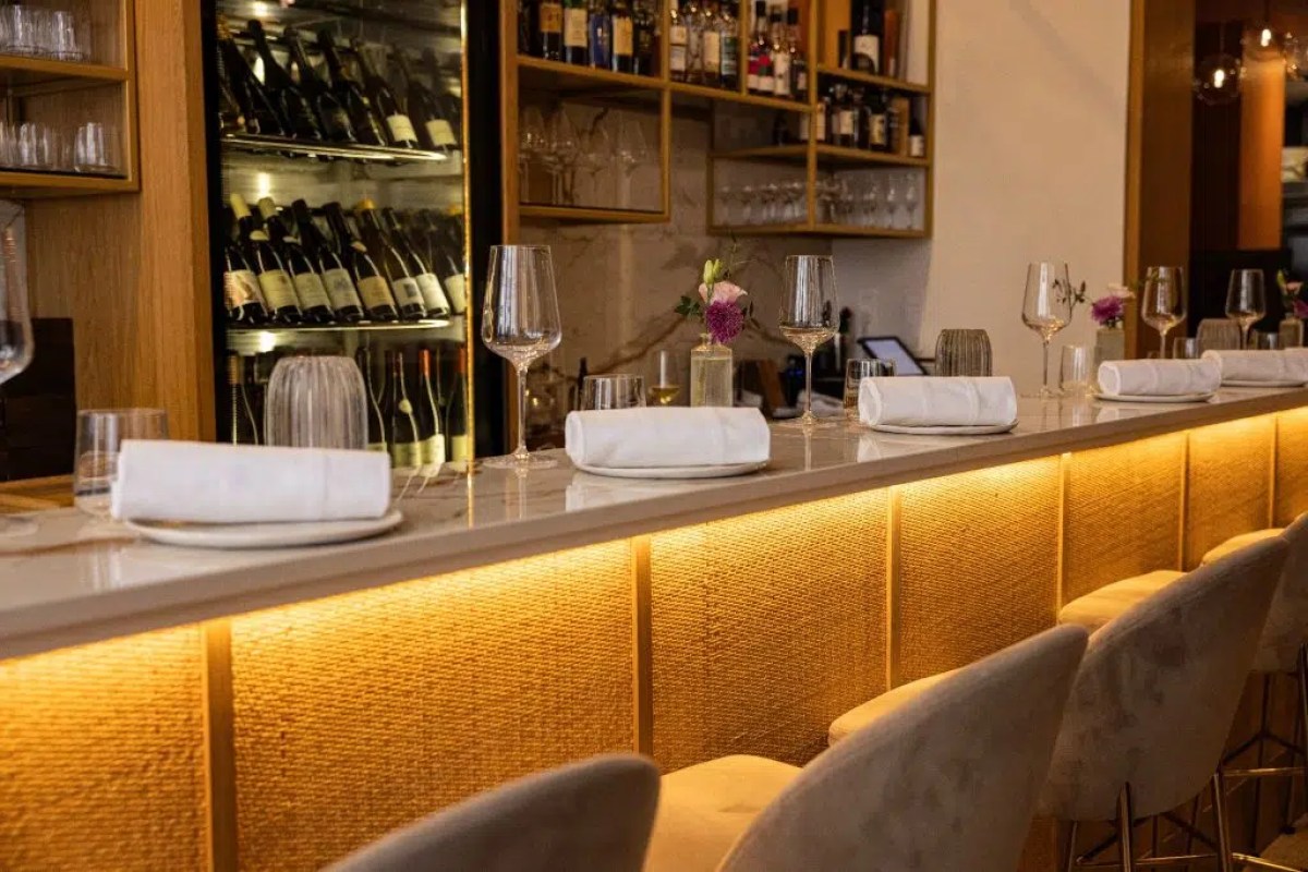 Restaurant bar counter with wine bottles, glasses, and place settings