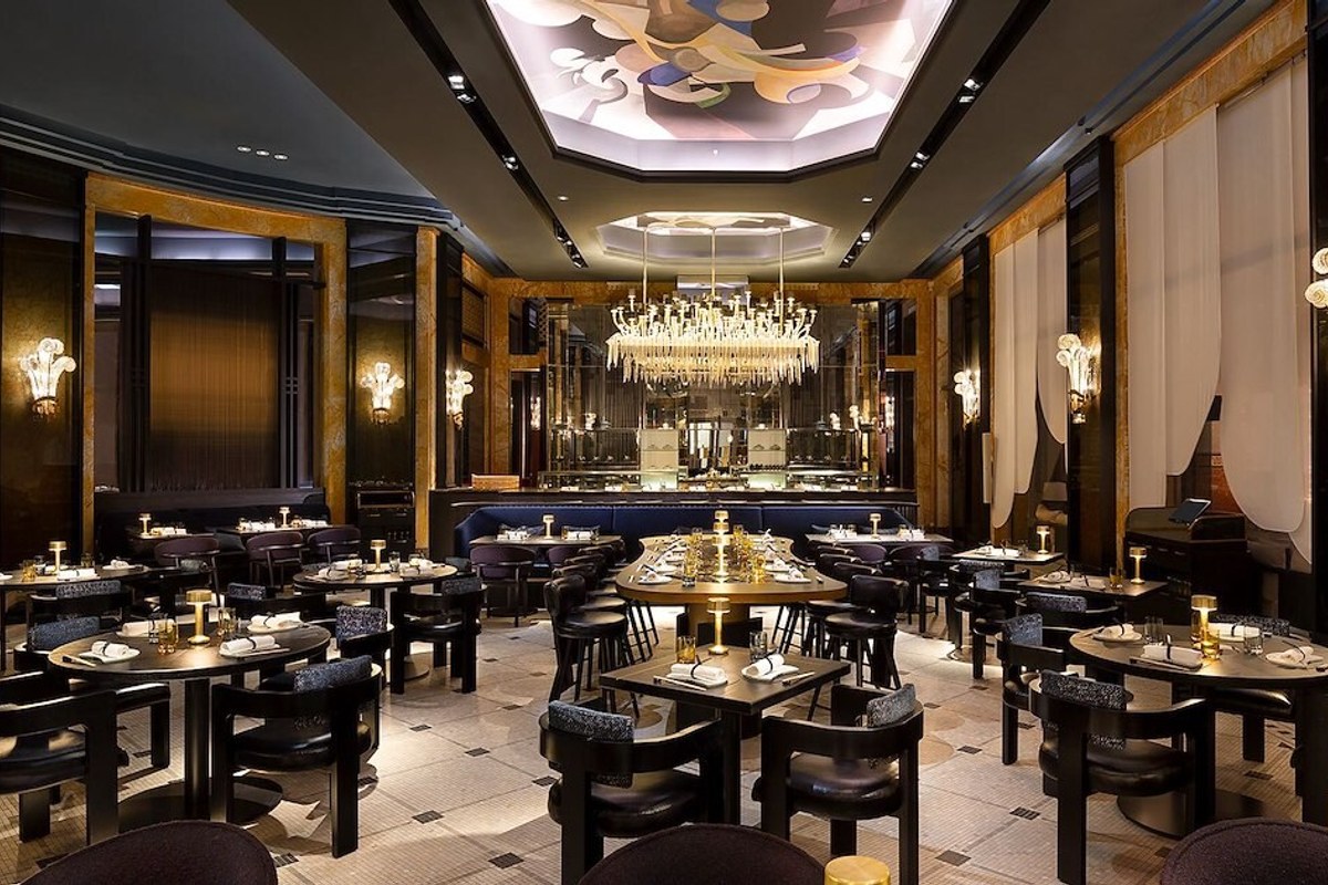 Elegant dining room with round tables, dark decor, ornate ceiling mural and central chandelier at Akira Back Paris