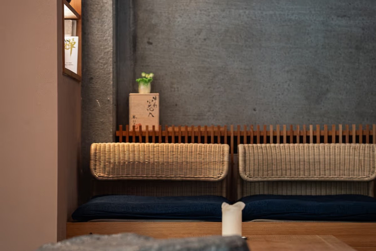 Cozy seating nook with woven rattan benches, dark blue cushions, and a textured concrete wall