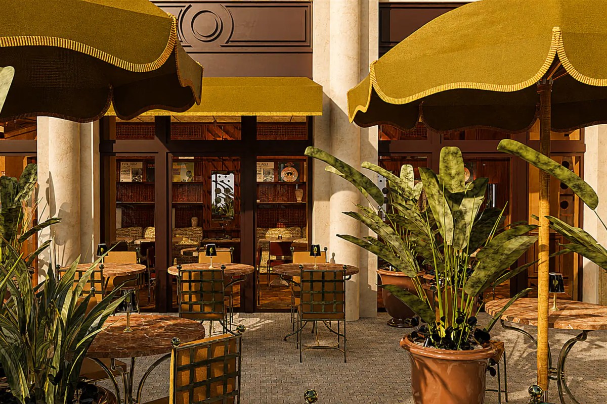 Full view of restaurant terrace with yellow umbrellas, marble tables, plants, and warm interior glimpse