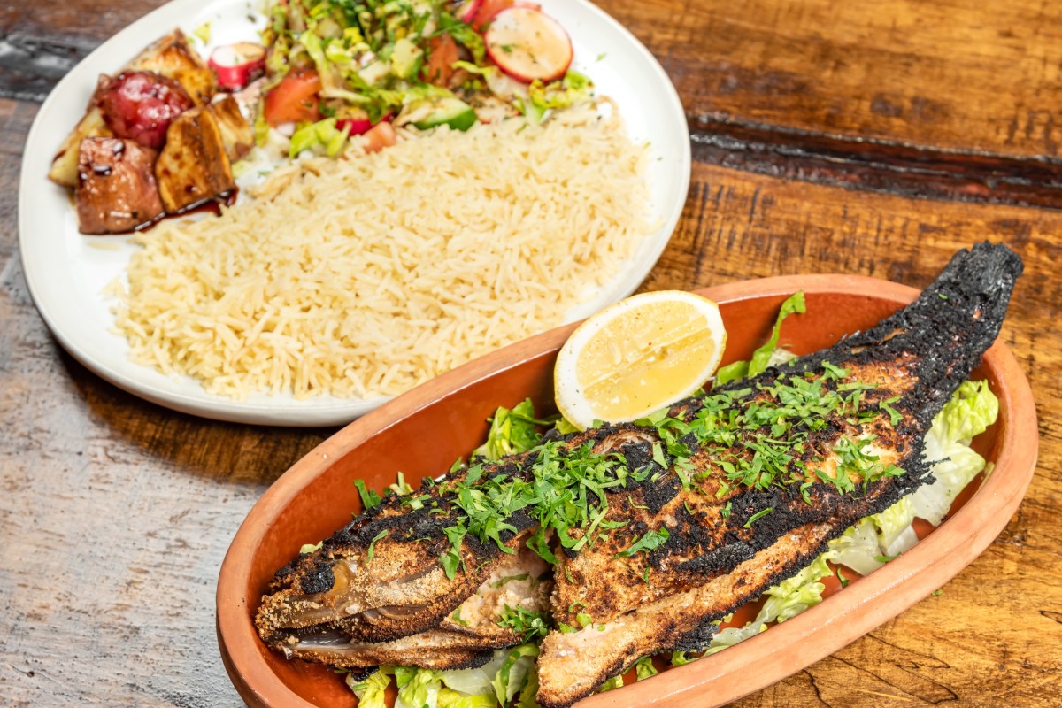 Grilled whole fish with herbs and lemon, plated with rice and salad