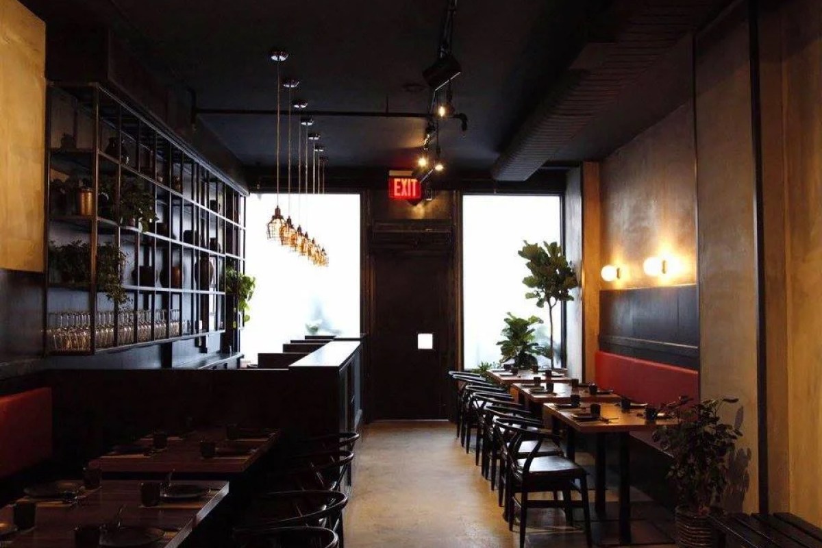Main dining room with bar shelving, booth seating, tables set, and exit sign