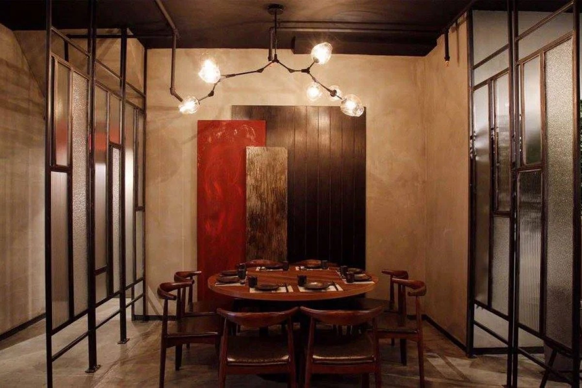 Private dining room with round wooden table, leather chairs, and artistic wall panels