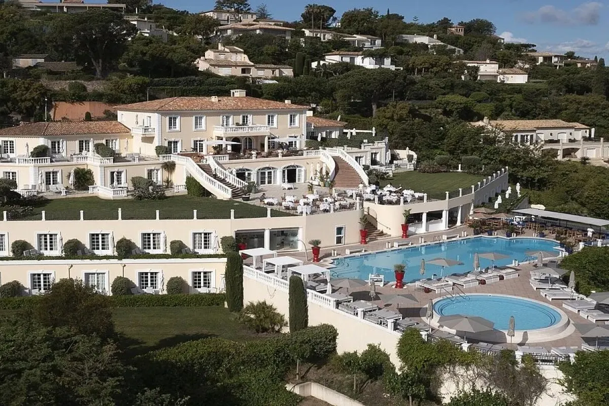 Aerial view of the hotel's cream-colored façade, staircases, dining terrace and swimming pool
