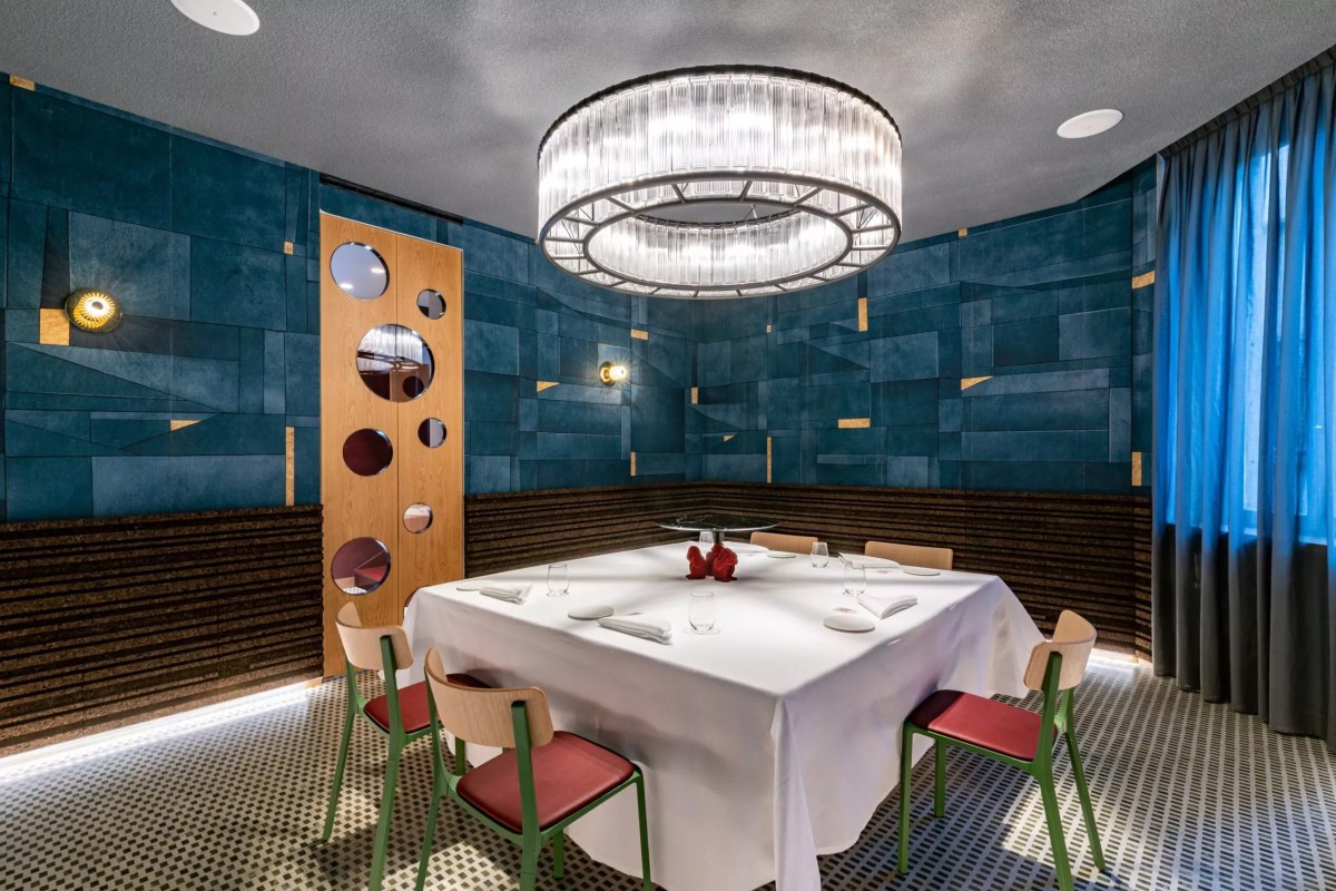 Elegant private dining room with teal padded walls, round chandelier, and set table