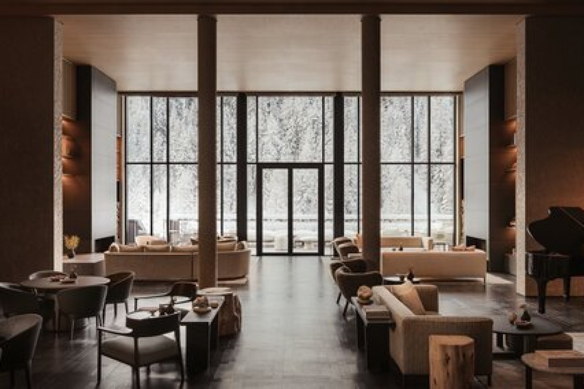 Elegant hotel lounge with grand piano, sofas and floor-to-ceiling windows overlooking snowy forest