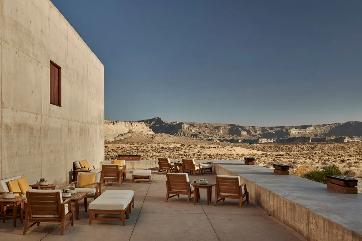 Concrete terrace with lounge chairs beside the hotel's facade overlooking the desert canyon landscape