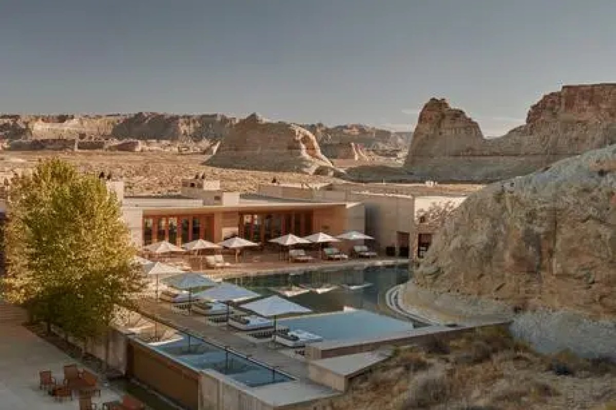 Amangiri building with pool, terrace and desert mountain backdrop at sunset.