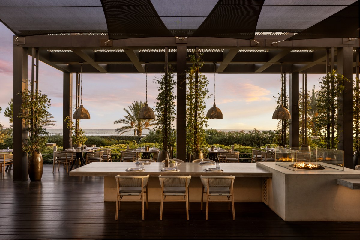 NEREA at Amara, a covered terrace restaurant with a long communal table and the sea beyond the garden