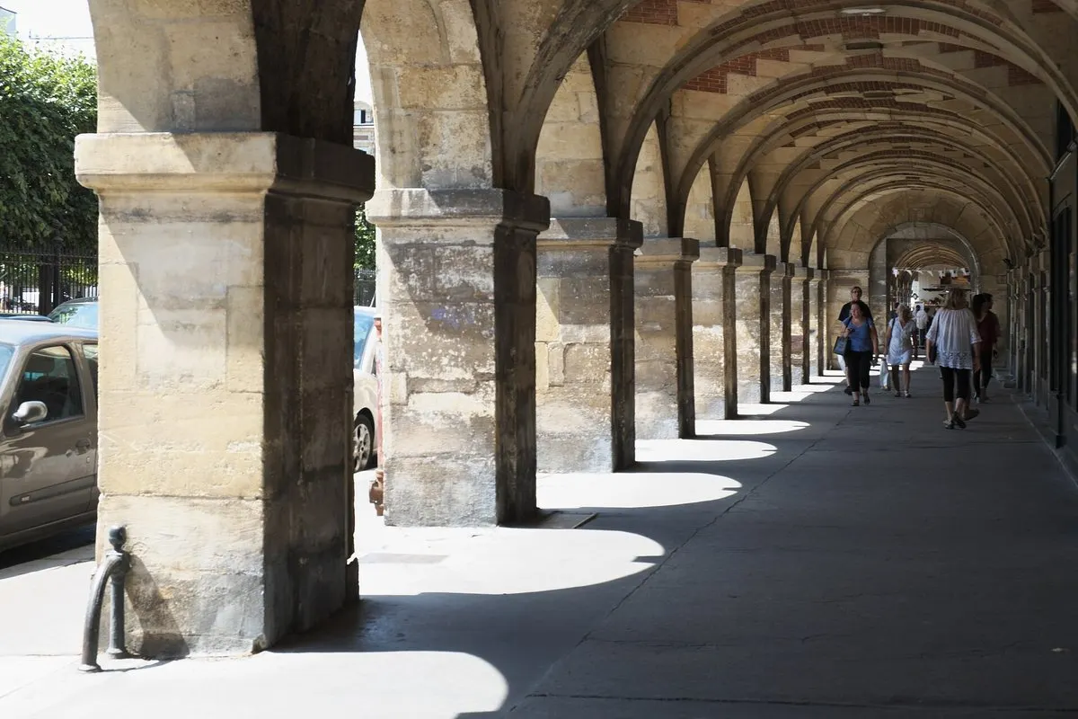 The stone arches under the arcades of Place des Vosges in Marais, Paris