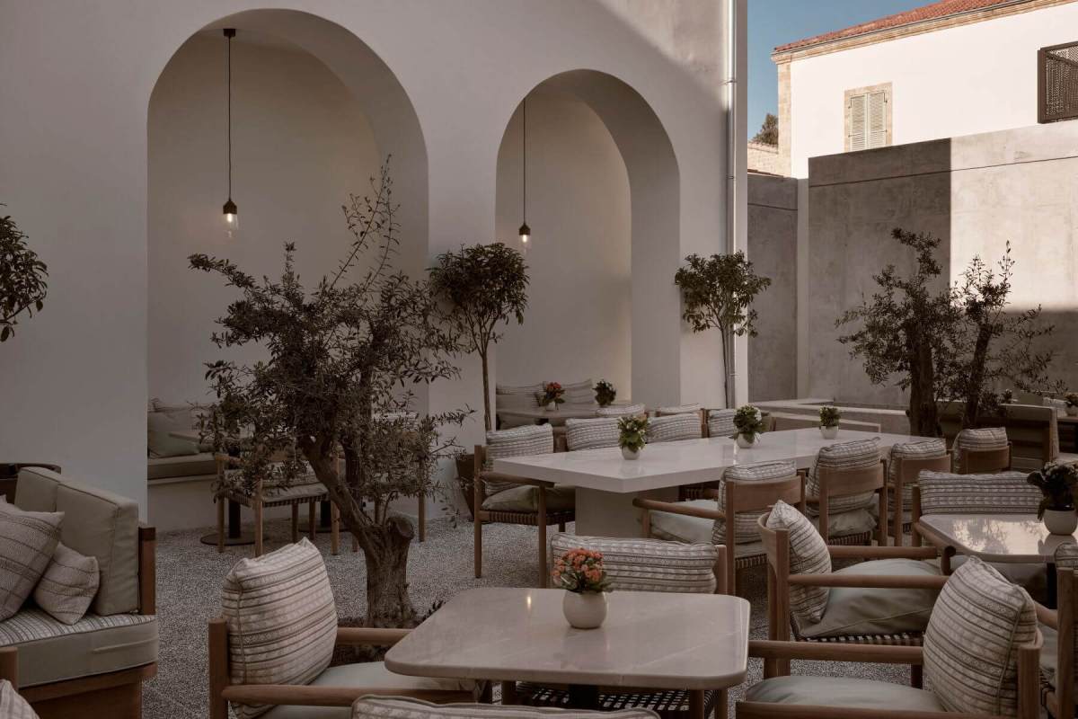 The courtyard of Amyth of Nicosia with olive trees, arched white walls and tables laid for Amyth Kouzina