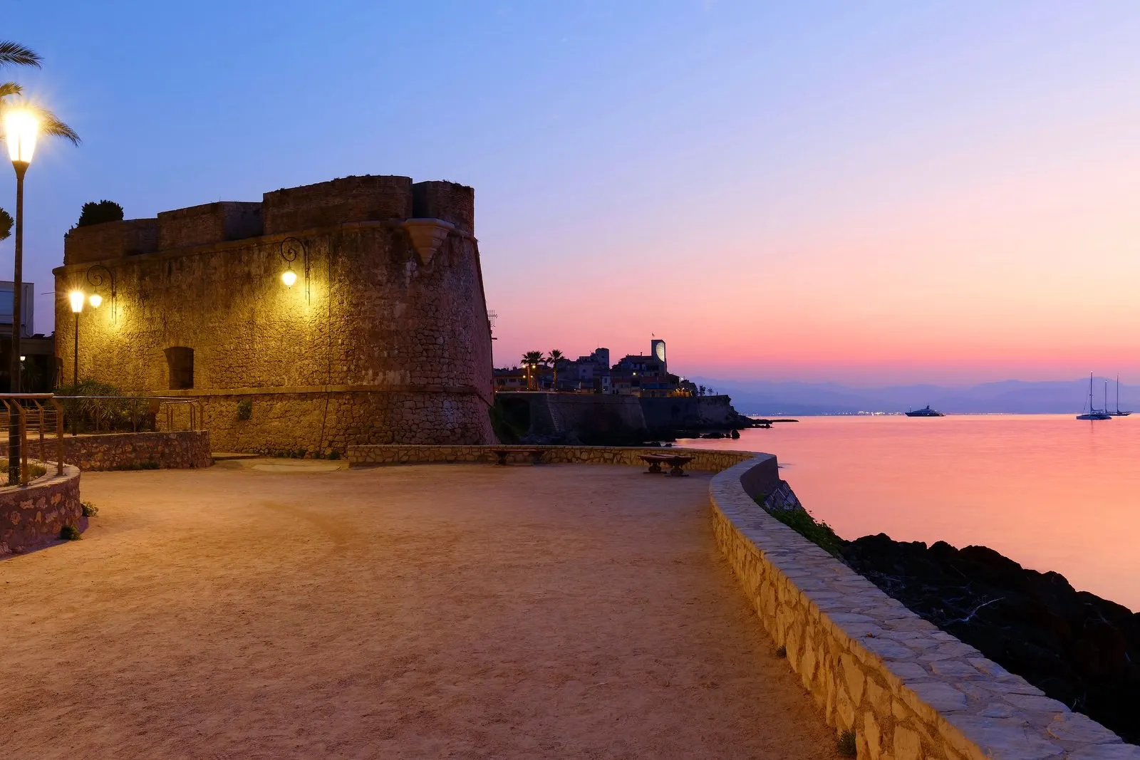 The ramparts of Old Antibes at dusk, the lights coming on along the sea wall