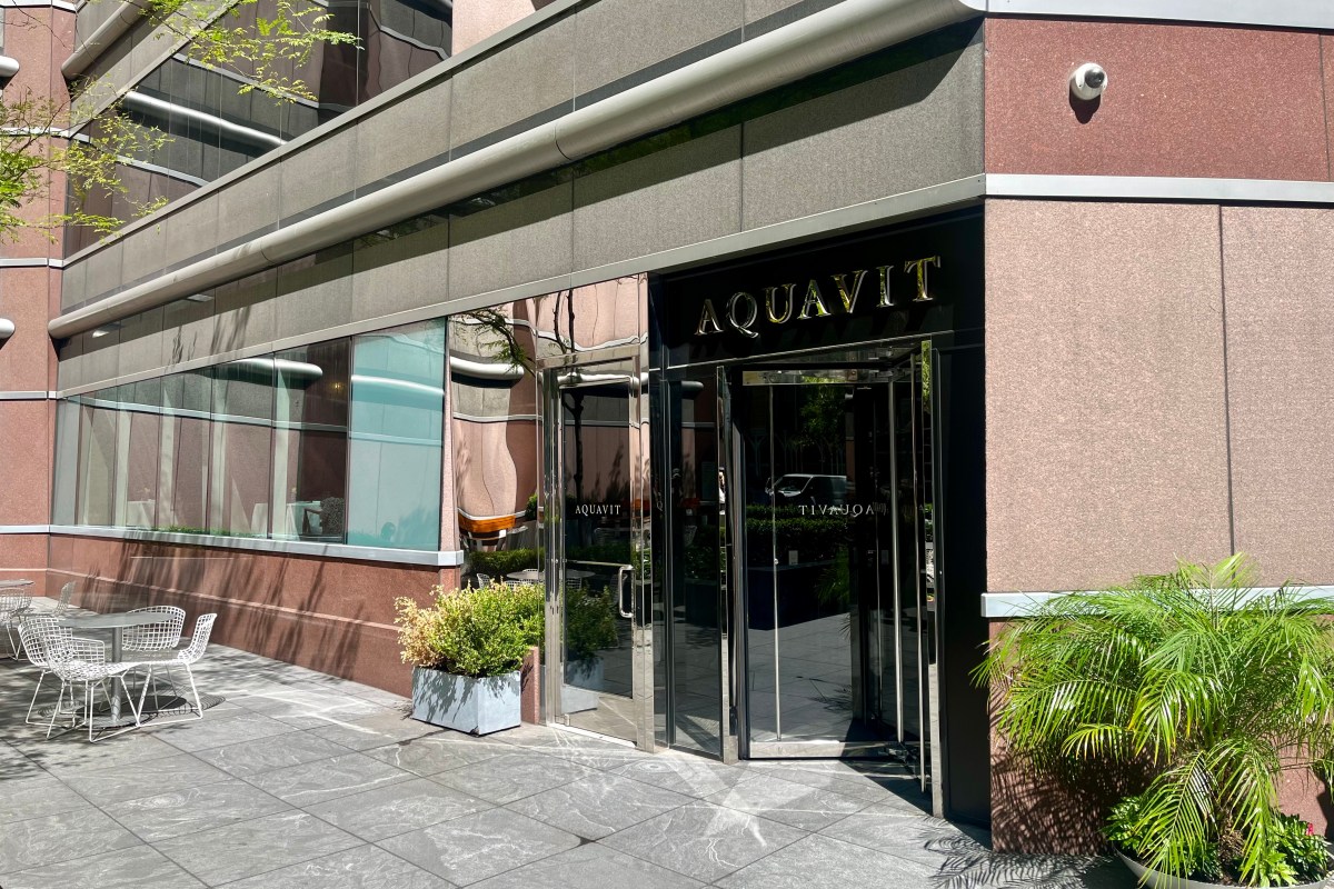 Aquavit restaurant exterior entrance with terrace seating, gold signage above revolving door