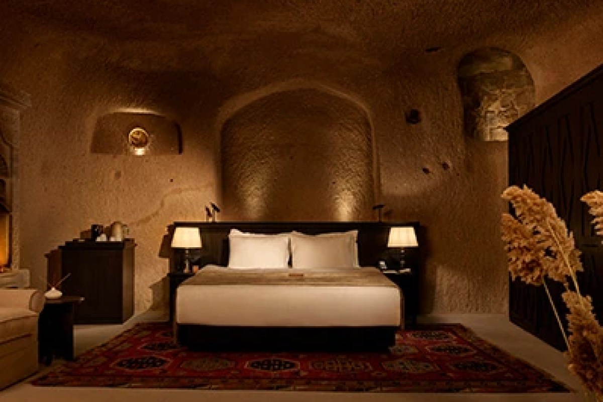 Cave-style guest room with carved stone walls, arched alcove, and elegant bed