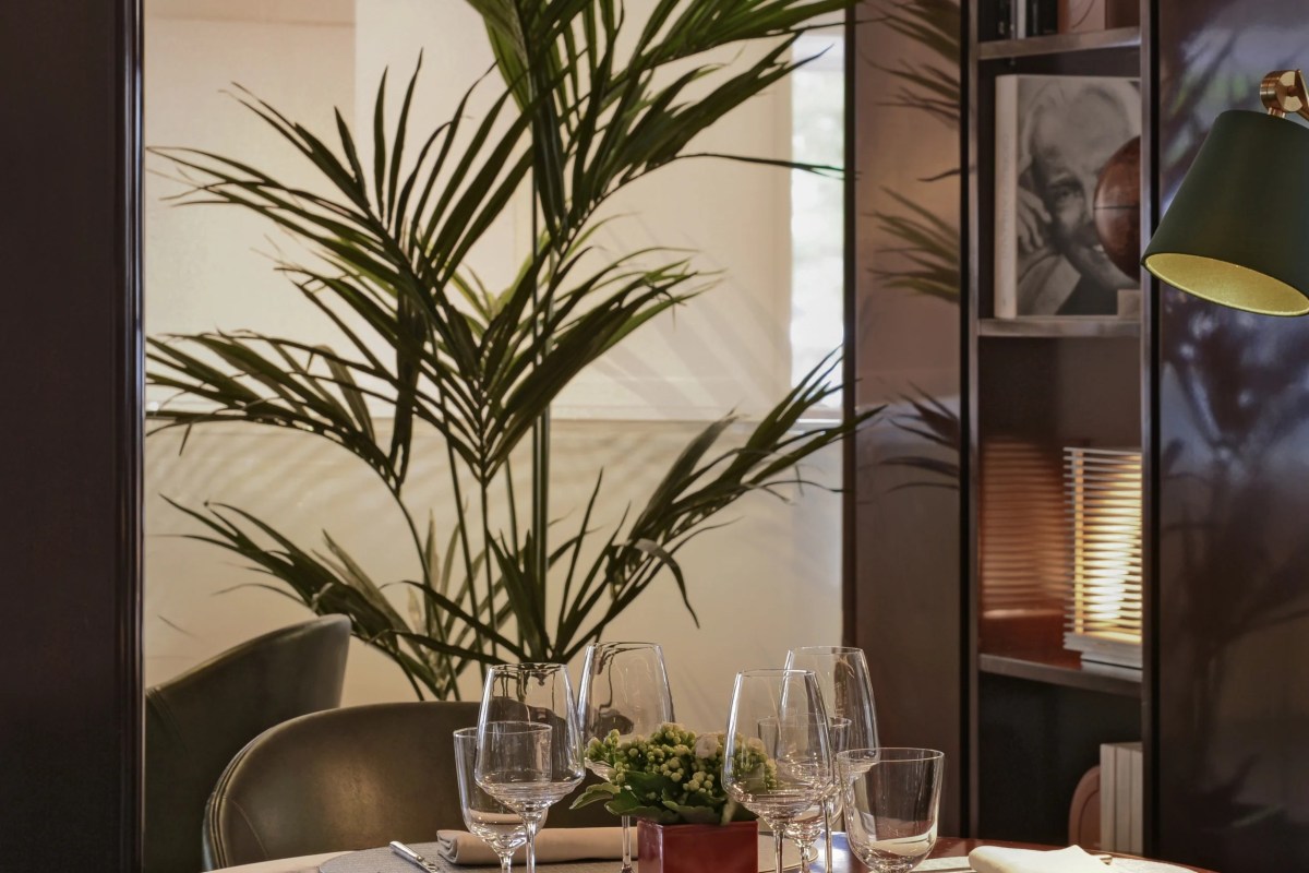 Elegant dining nook with a palm plant, wine glasses, and a small flower centerpiece on a table