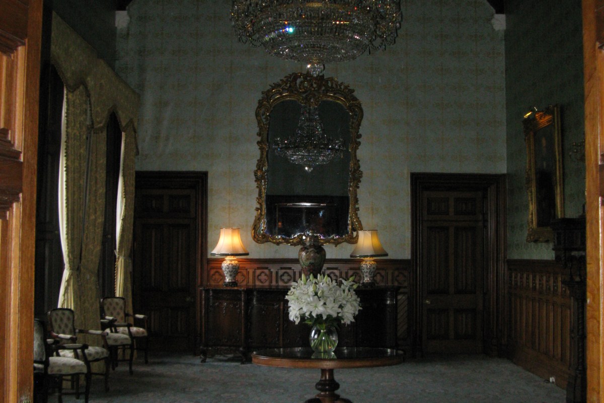 Elegant interior hall with chandelier, mirror, lamps and flowers