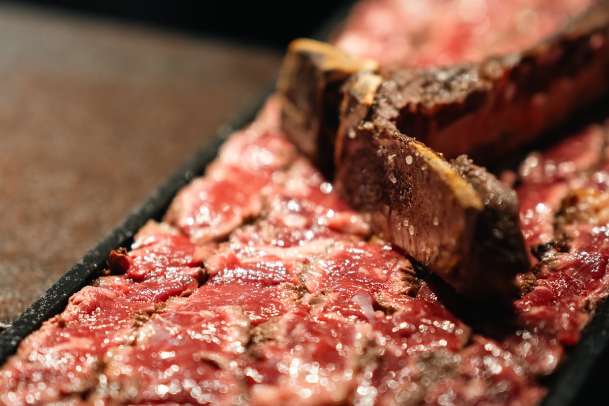 Grilled T-bone steak sliced on a board, close-up view